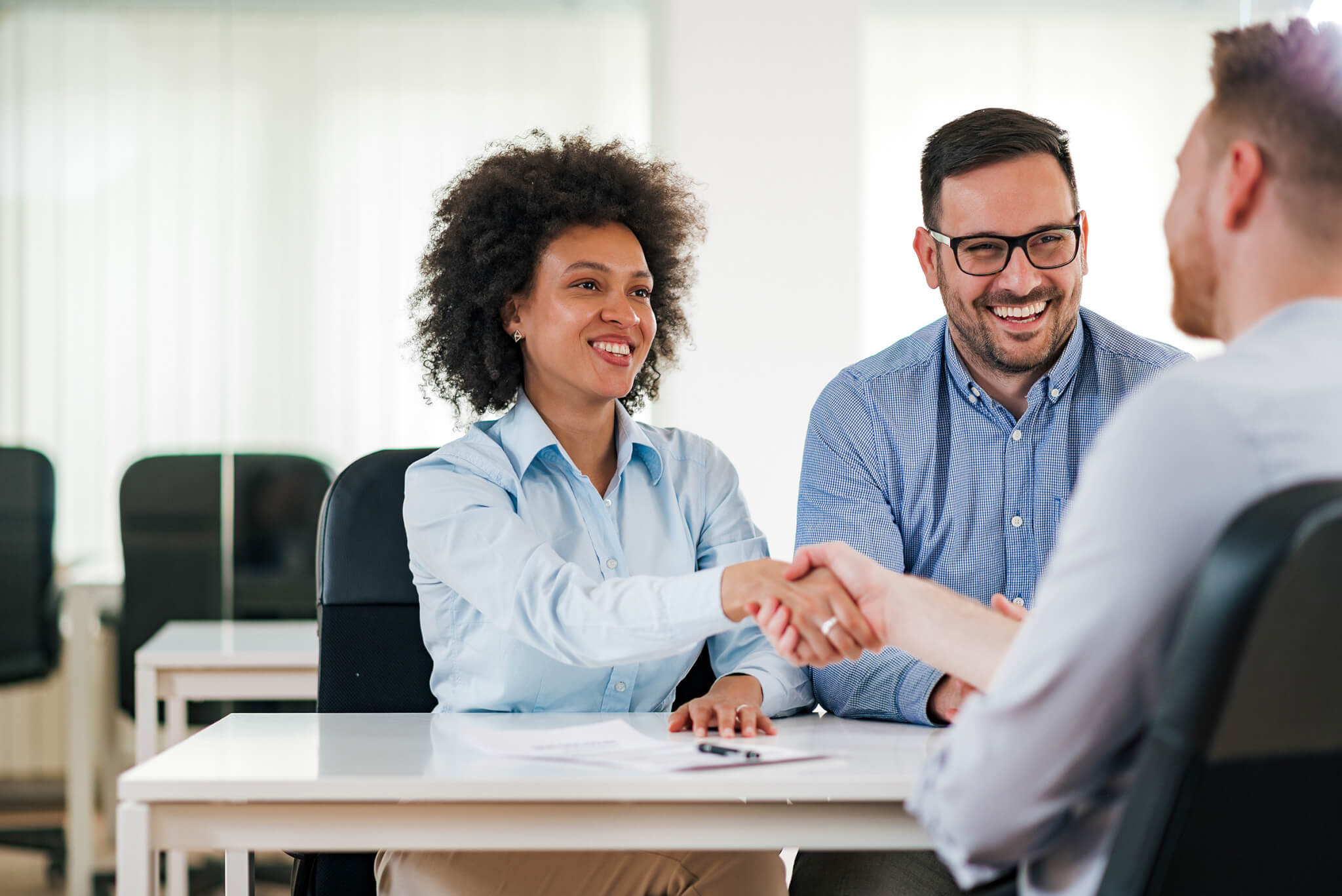 Smiling HR managers handshake with a job candidate.